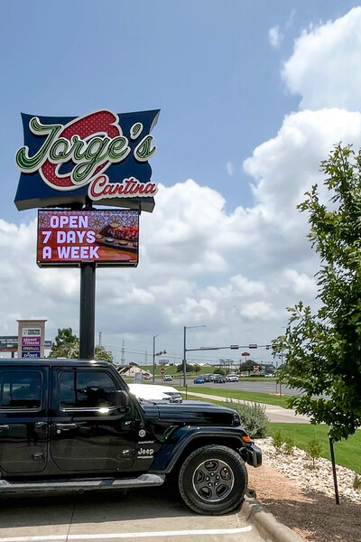 Freestanding restaurant sign with a digital message display beside a road
