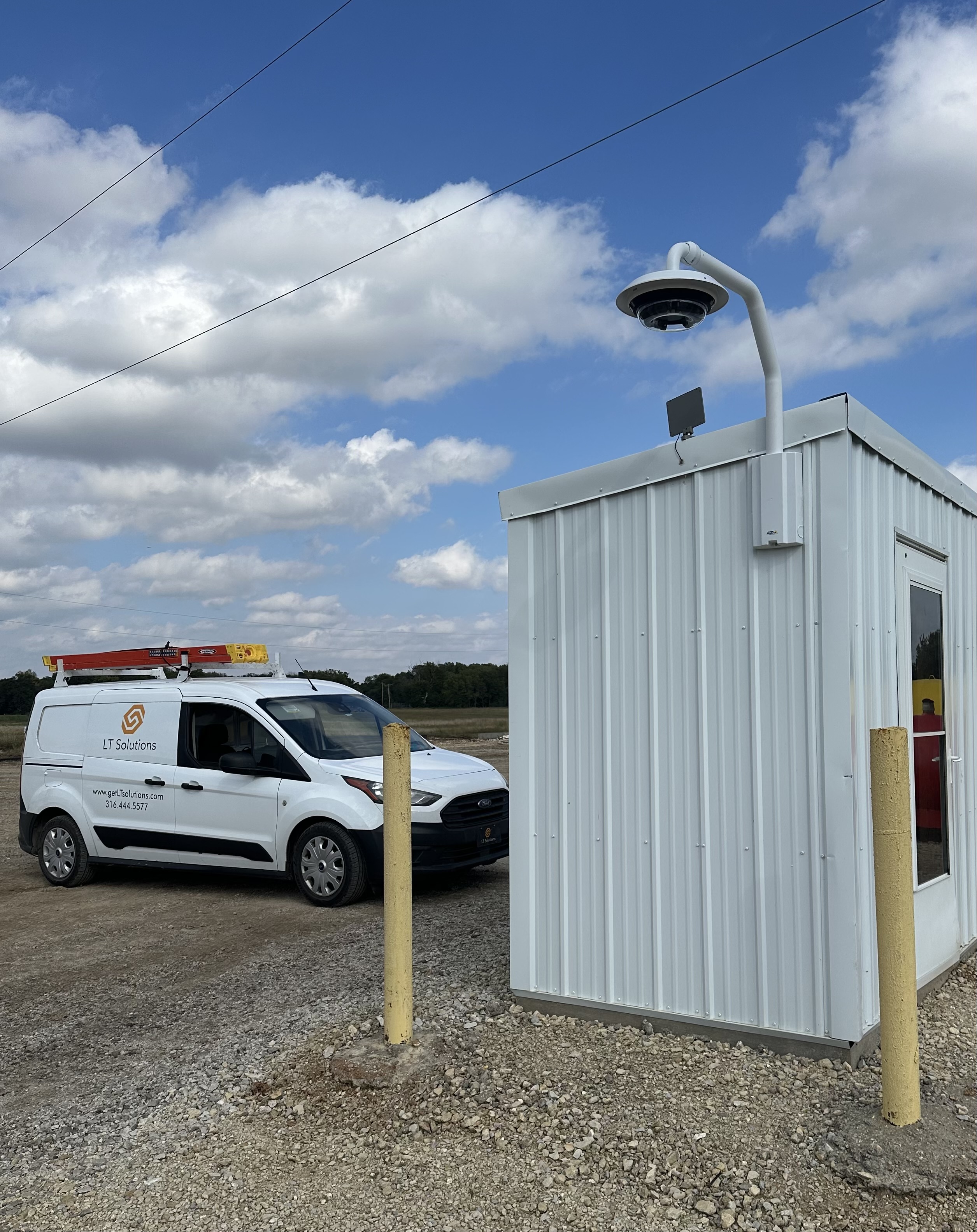 Pole-mounted light beside a small metal building with an LT Solutions van nearby